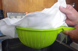 A colander is lined with butter muslin to accept the curds.