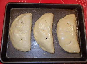 Calzone ready for the oven with a light coating of olive oil and slits to vent steam.