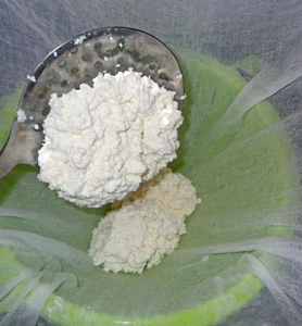 The curds are ladled into a cheesecloth lined colander for draining.