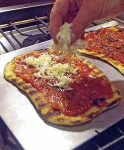 Grated homemade mozzarella is sprinkled on the pizza. 