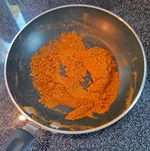 Toasting ground spices to enhance flavor.